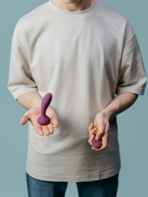 Adult holding two different purple vibrators, promoting self-love and sexual wellness.