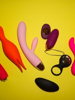 Studio setup showcasing colorful sex toys on a bright yellow background, featuring various shapes and designs.